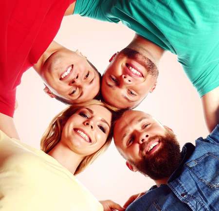 Happy, smiling friends standing together and looking at camera over orange background.の写真素材