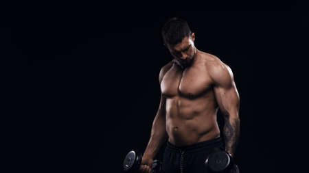 Fit and sporty bodybuilder over black background. Sportsman in studio. Sport and fitness concepts.の写真素材