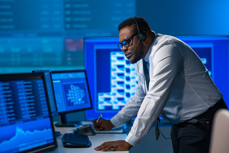 African-American broker works in office using workstation and analysis technology. Workplace of professional trader. Global financial markets, business, currency exchange and banking concepts.の写真素材