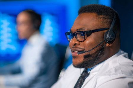 Call-center worker is speaking with the client by headset. Workplace of the african-american support...