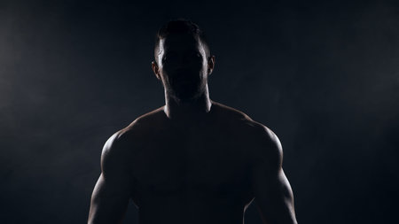 Fit and sporty bodybuilder over black background. Sportsman in studio. Sport and fitness concepts.の写真素材