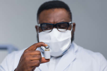 Professional African-American scientist is working on a vaccine in a modern scientific research laboratory. Doctor is looking on a vaccine tube. Future technology and science.の写真素材