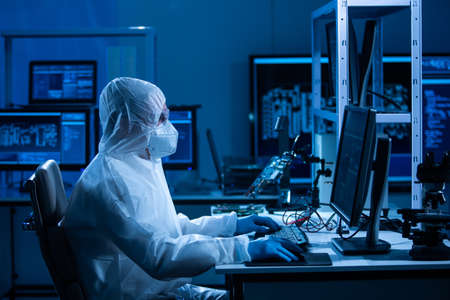 Microelectronics engineer works in a modern scientific laboratory on computing systems and microprocessors. Electronic factory worker is testing the motherboard and coding the firmware.の写真素材