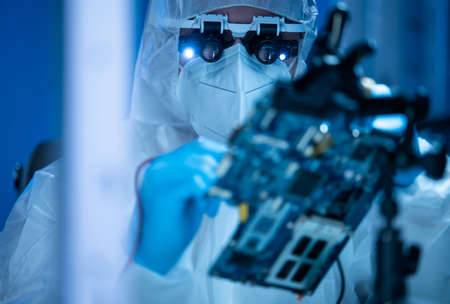 Microelectronics engineer works in a modern scientific laboratory on computing systems and microprocessors. Electronic factory worker is testing the motherboard and coding the firmware.の写真素材