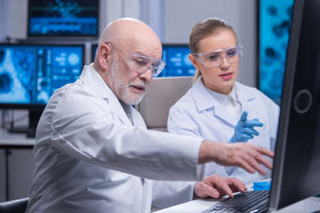 Professor and his young and professional laboratory assistant are doing scientific experiment in a modern laboratory. Genetic engineers workplace. The concept of science, medicine and vaccine.の写真素材