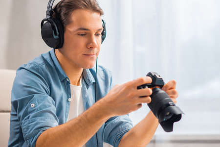 Freelance photographer workplace at home office. Young man works using computer, graphic tablet, camera and other devices. Remote job.の写真素材