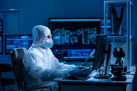 Microelectronics engineer works in a modern scientific laboratory on computing systems and microprocessors. Electronic factory worker is testing the motherboard and coding the firmware.の写真素材