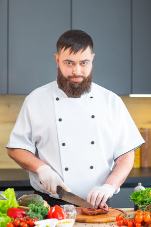 Young chef is cutting octopus in a modern kitchen. The man prepares food at home. Cooking healthy...