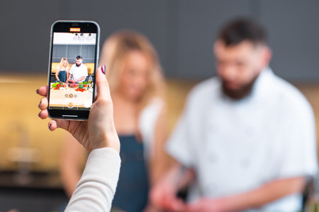 Young woman and man prepare food and host a cooking show. The bloggers stream from modern kitchen. Healthy food preparation.の写真素材