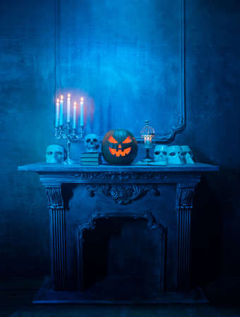 Scary laughing pumpkin and old skull on ancient gothic fireplace. Halloween, witchcraft and magic.の写真素材