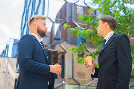 Confident businessman and his colleague in front of modern office building. Financial investors are talking outdoor. Banking and business.の写真素材