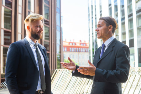 Confident businessman and his colleague in front of modern office building. Financial investors are talking outdoor. Banking and business.の写真素材