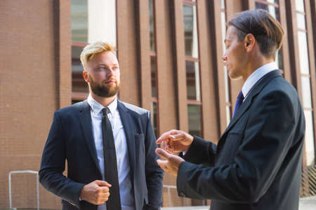 Confident businessman and his colleague in front of modern office building. Financial investors are talking outdoor. Banking and business.の写真素材