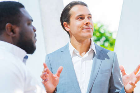African-American businessman and his colleague in front of modern office building. Financial investors are talking outdoor. Banking and business concept.の写真素材