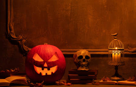 Scary laughing pumpkin and old skull on ancient gothic fireplace. Halloween, witchcraft and magic.の写真素材