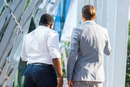 African-American businessman and his colleague in front of modern office building. Financial...