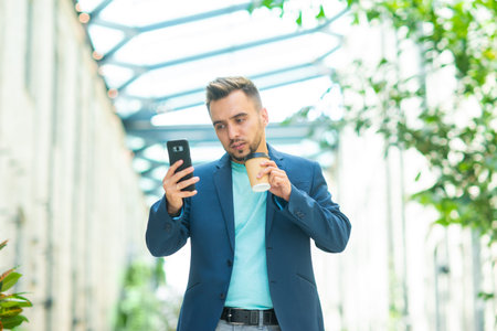 A young successful businessman is working outdoor using smartphone. Man in a casual wear. Business,...