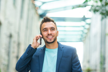A young successful businessman is working outdoor using smartphone. Man in a casual wear. Business,...