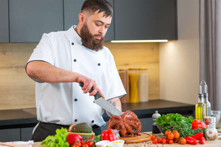 Young chef is cutting octopus in a modern kitchen. The man prepares food at home. Cooking healthy and tasty food.の写真素材