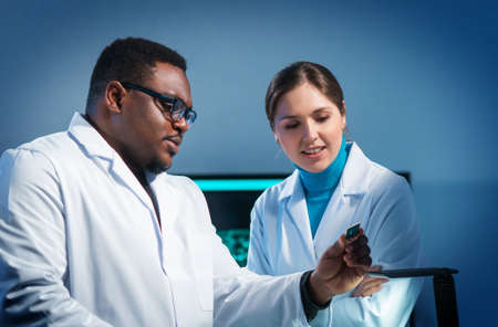 Group of microelectronic engineers discussing in a modern microprocessor manufacture lab. Workplace of electronics designers. The concept of innovations and inventions.の写真素材