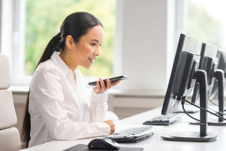 Asian business woman is working at her table in a modern office. The workplace of a successful specialist. Business, confidence and finance.の写真素材
