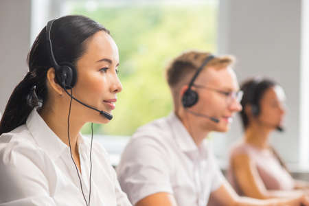 Diverse team of young professionals is working in the phone support office. Working day of sales managers in the call center. Business, telephone consulting and problem solving.の写真素材