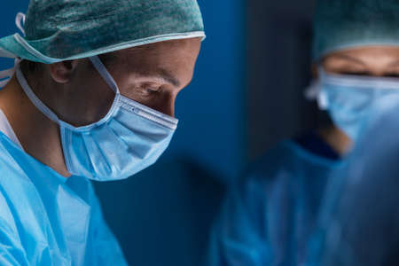 Multiracial team of professional medical surgeons performs the surgical operation in a modern hospital. Doctors are working to save the patient. Medicine, health, cardiology and transplantation.の写真素材