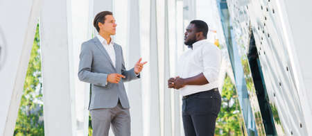 Finance, business and cooperation concept. Two successful businessmen are talking on the street. Office workers are discussing business issues outdoor.の写真素材