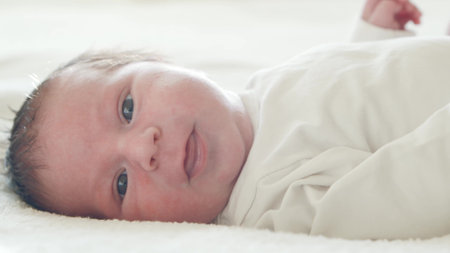 Close-up portrait of a young baby who has recently been born. Newborn infant boy at home. Window...