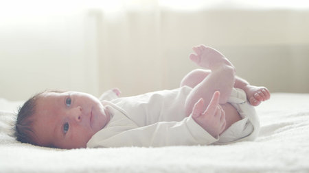 Close-up portrait of a young baby who has recently been born. Newborn infant boy at home. Window...
