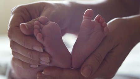 Close-up feet of a nursing baby who has recently been born. Newborn infant boy at home. Window light.の写真素材