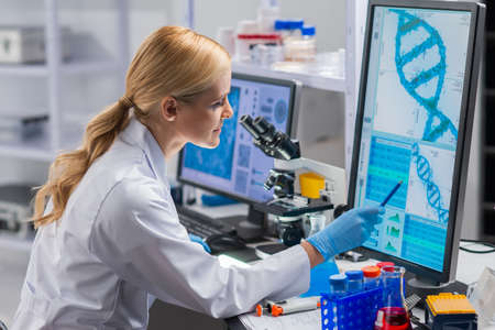 Professional female scientist is working on a vaccine in a modern scientific research laboratory. Genetic engineer workplace. Future technology and science.の写真素材