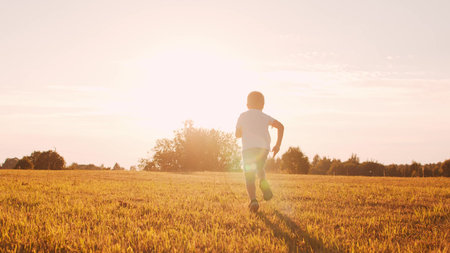 Boy in a field at sunset. The concept of childhood, freedom and inspiration.の写真素材