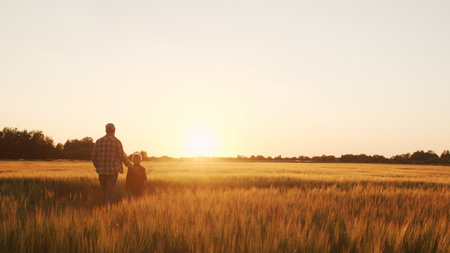 Farmer and his son in front of a sunset agricultural landscape. Man and a boy in a countryside...