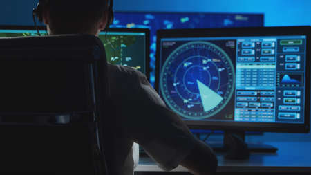 Workplace of the professional air traffic controller in the control tower. Caucasian aircraft control officer works using radar, computer navigation and digital maps. Aviation concept.の写真素材