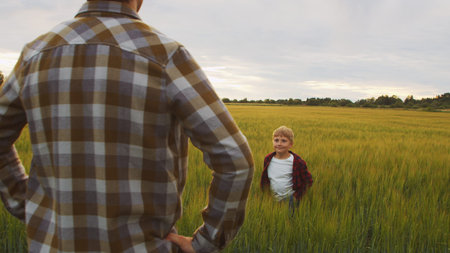 Farmer and his son in front of a sunset agricultural landscape. Man and a boy in a countryside...