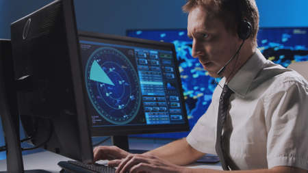 Workplace of the professional air traffic controller in the control tower. Caucasian aircraft control officer works using radar, computer navigation and digital maps. Aviation concept.の写真素材