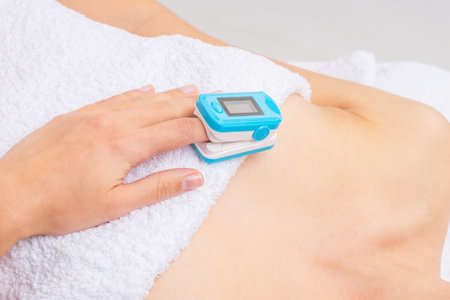 Woman using pulse oximeter at home. Female hand and medical equipment. Healthcare concept.の写真素材