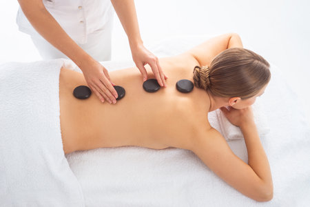 Young woman getting massaging treatment over white. Spa, healthcare and recreation concept.の写真素材