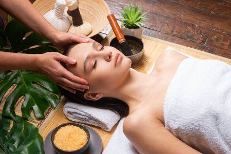 Young woman getting massaging treatment over exotic background. Spa, healthcare and recreation concept.の写真素材