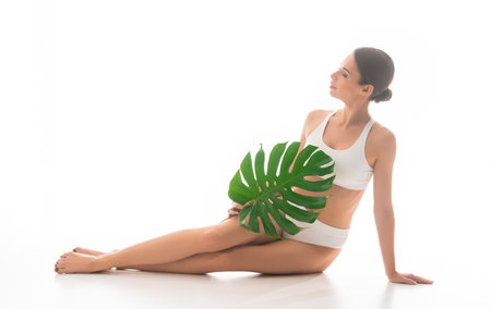 Young, fit and beautiful brunette woman in white swimsuit isolated on white background.の写真素材