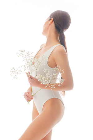 Young, fit and beautiful brunette woman in white swimsuit isolated on white background.の写真素材