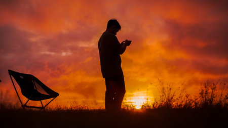 Silhouette of a man with a mobile phone at sunset.