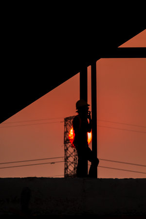 Silhouette of engineer working on the construction site at sunset.の写真素材
