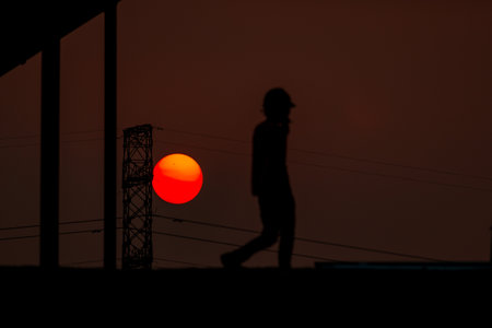Silhouette of construction worker at sunset with building silhouettes.の写真素材