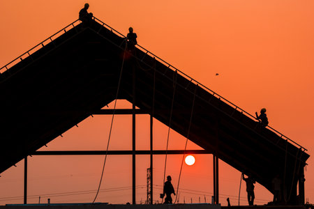 silhouette of construction workers working on the construction site at sunsetの写真素材