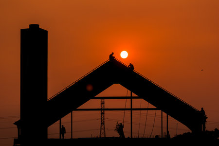 silhouette of construction workers working on the building site at sunsetの写真素材