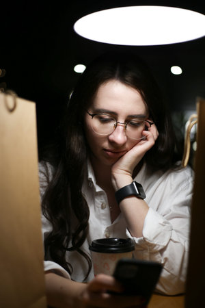 a young woman sits among paper bags with purchases and looks at the phone