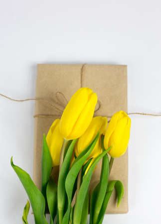 bouquet of yellow tulips on a wrapped gift on a white backgroundの写真素材