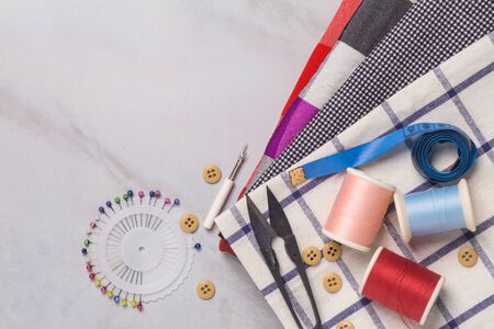 sewing tools : the fabric, scissors, pins, tape measure, threads on tailor desk, top viewの写真素材